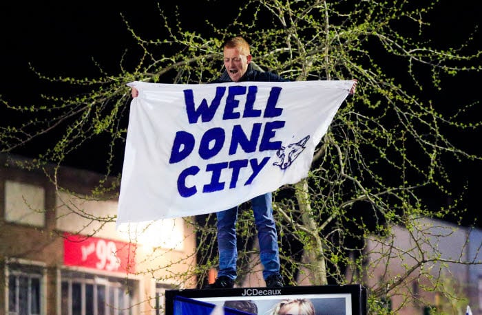 A Leicester City fan stands on top of an advertising board near the clock tower in Leicester after seeing their side crowned Barclays Premier League champions following Tottenham Hotspur's 2-2 draw against Chelsea. Photo : Jonathan Brady / PA Images / Icon Sport
